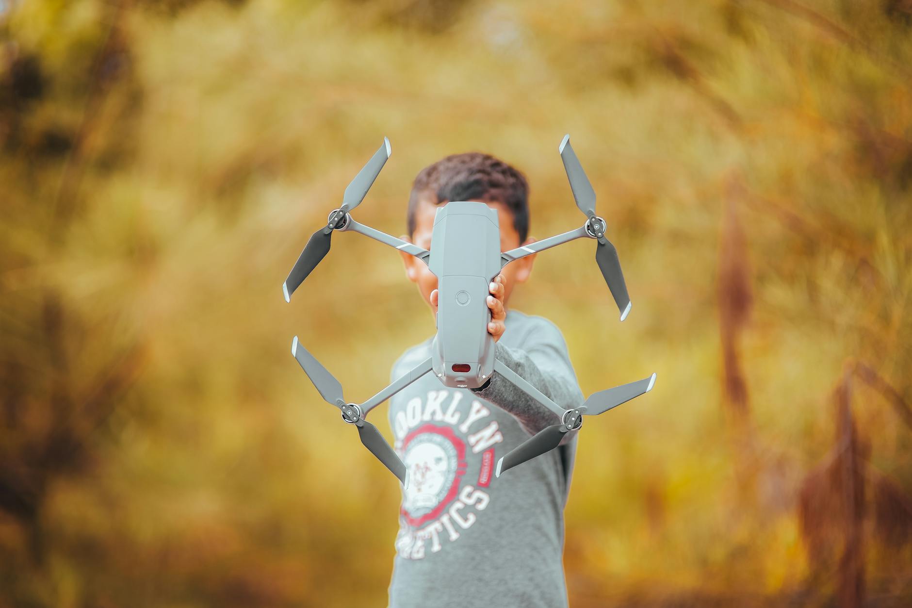 a person holding a gray done camera