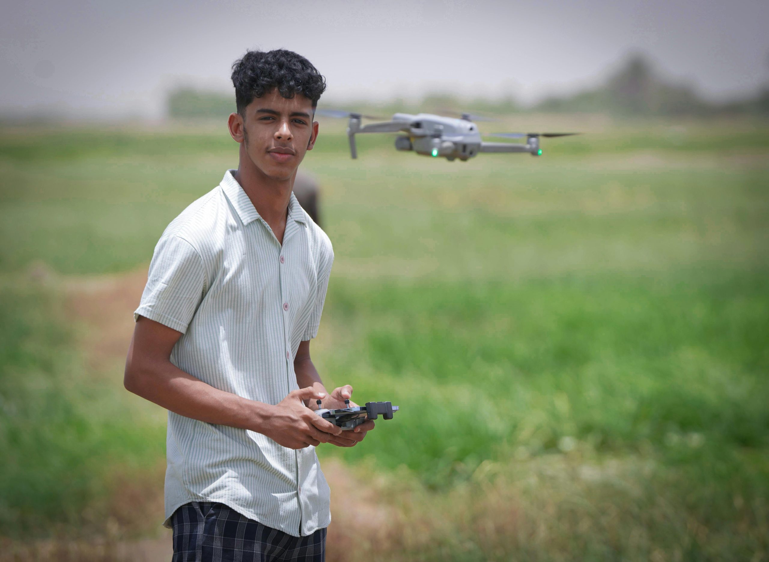 A young man operates a drone in a rural outdoor setting, embracing modern technology.
